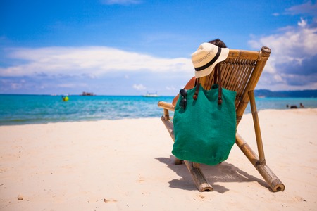 Young man relaxing in wooden chair on white sand beachの写真素材