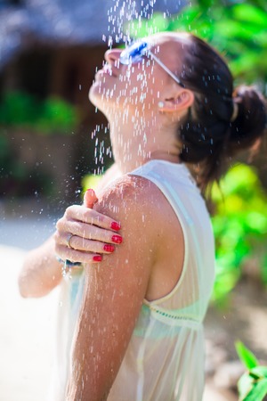 Young happy woman in tropical shower during beach vacaionの写真素材