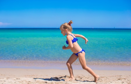 Adorable little girl have fun on tropical white sandy beachの写真素材