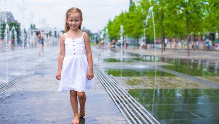 Little girl having fun in outdoor fountain at hot dayの写真素材