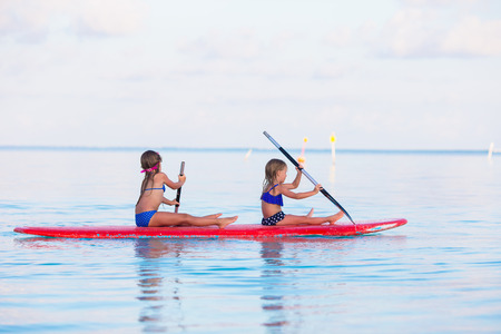 Little girls swimming on surfboard during summer vacationの写真素材