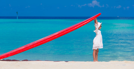 Adorable little girl with red big surfboard during tropical vacationの写真素材