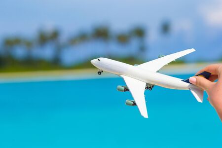 Little white toy airplane on background of turquoise seaの写真素材