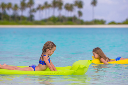 Adorable little girls on air inflatable mattress in the seaの写真素材
