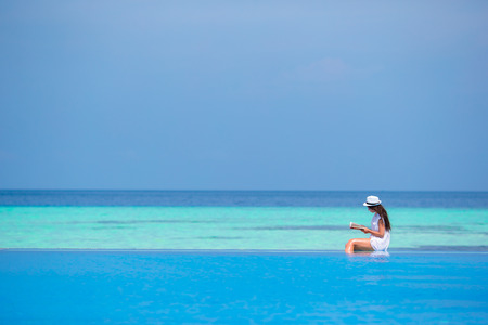 Young girl reading book near swimming poolの写真素材