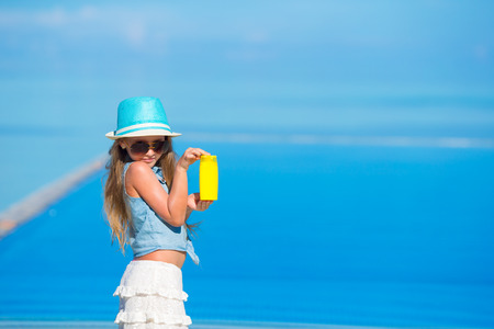 Cute little girl with sunblock at beach during summer vacation