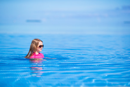 Smiling adorable girl having fun in outdoor swimming poolの写真素材