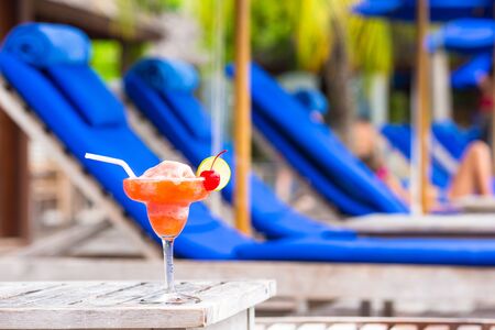 Tasty cocktail on wooden table near swimming poolの写真素材