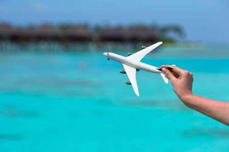 Little white toy airplane on background of turquoise seaの写真素材