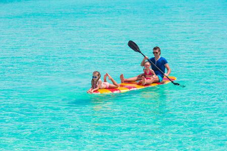 Little girls and young dad on surfboard during summer vacationの写真素材