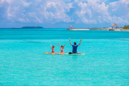 Little girls and young dad on surfboard during summer vacationの写真素材