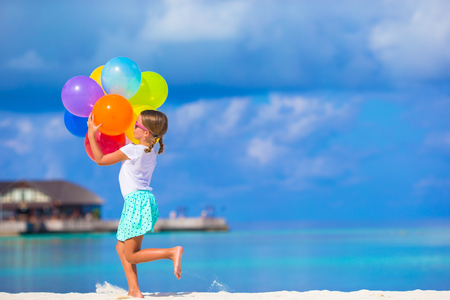 Cute little girl playing with balloons at the beachの写真素材