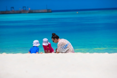Young mom and little girls playing on white sandy beachの写真素材