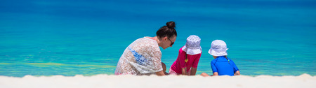 Young mom and little girls playing on white sandy beachの写真素材