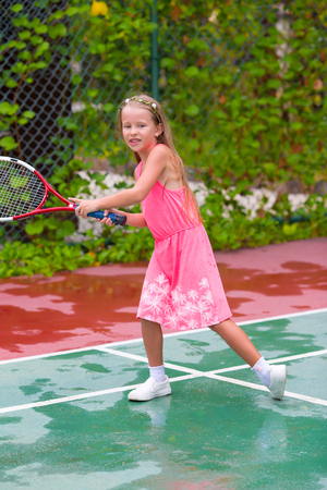 Little girl playing tennis on the courtの写真素材