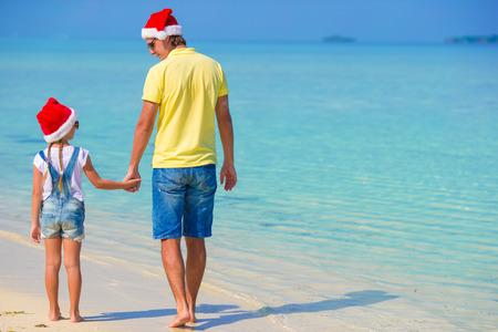 Little girl and happy dad in Santa Hat during beach vacationの写真素材