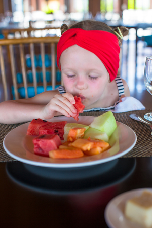 Adorable little girl having breakfast at outdoor cafeの写真素材