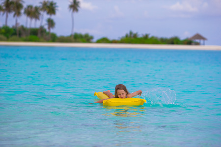 Adorable little girl on air inflatable mattress in the sea