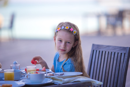 Adorable little girl having breakfast at outdoor cafeの写真素材
