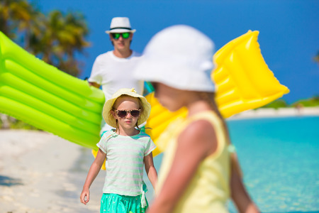 Happy father and his adorable little daughters at tropical beach having funの写真素材