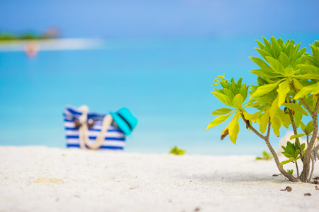 Beach accessories - blue bag, straw hat, sunglasses on white beachの写真素材