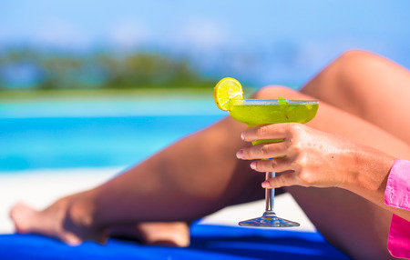 Young woman with tasty cocktail on beach loungersの写真素材