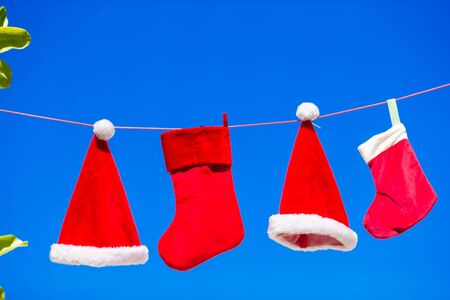Red Santa hats and Christmas stocking hanging on tropical beachの写真素材