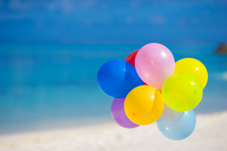 Multicolored balloons on white tropical beachの写真素材