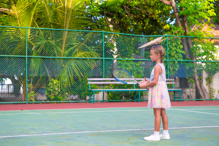 Little girl trying to play tennis on outdoor courtの写真素材