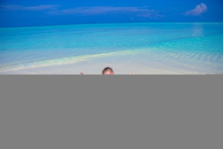 Adorable happy little girl have fun at shallow water on beach vacationの写真素材