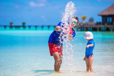 Happy father and little daughter have fun on tropical beachの写真素材