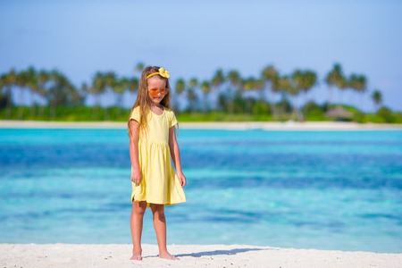 Adorable happy little girl have fun at shallow water on beach vacationの写真素材
