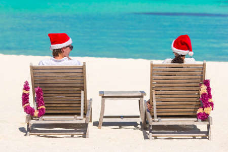 Back view of young couple in Santa hats relaxing on tropical beach during Christmas vacationの写真素材