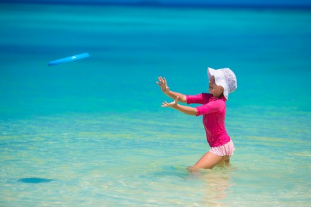 Little girl playing with flying disc at white beachの写真素材