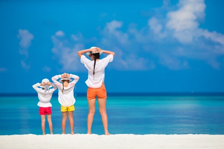 Adorable little girls and young mother on tropical white beachの写真素材