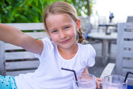 Little girls taking selfie and drinking tasty cocktails at outdoor cafeの写真素材