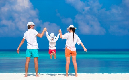 Young family of three on white beach during tropical vacationの写真素材