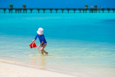 Adorable happy little girl have fun at shallow water on beach vacationの写真素材