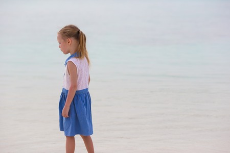 Adorable happy little girl have fun at shallow water on beach vacationの写真素材