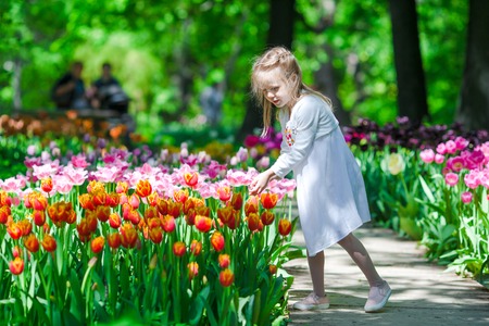 Little beautiful girl in tulips garden at warm spring dayの写真素材