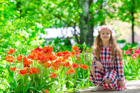 Little beautiful girl in tulips garden at warm spring dayの写真素材