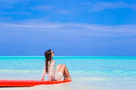 Young surfer woman at white beach on red surfboardの写真素材