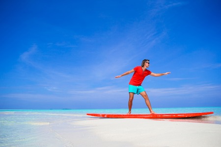 Happy young man practicing surfing position on surfboard