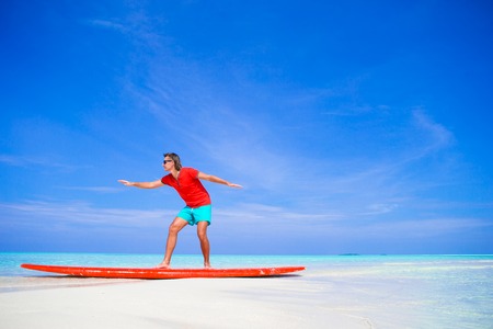 Happy young man practicing surfing position on surfboardの写真素材