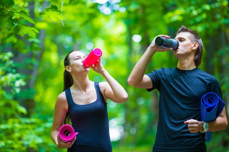 Jogging active couple have a rest with mat and bottle of water outdoors in forestの写真素材