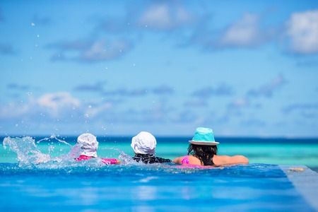 Mother and two kids enjoying summer vacation in luxury swimming poolの写真素材