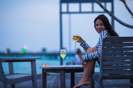 Young girl with white wine at evening outdoor cafeの写真素材