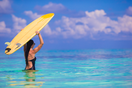 Happy shapely surf woman at white beach with yellow surfboardの写真素材
