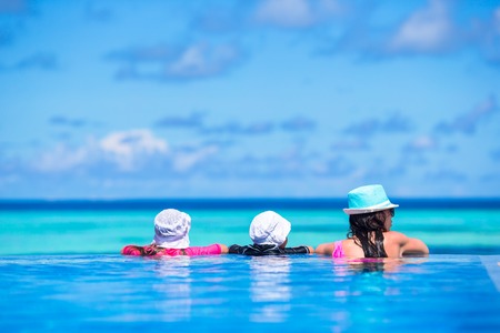 Mother and two kids enjoying summer vacation in luxury swimming poolの写真素材