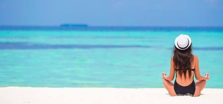Young woman sitting in yoga position during tropical vacationの写真素材